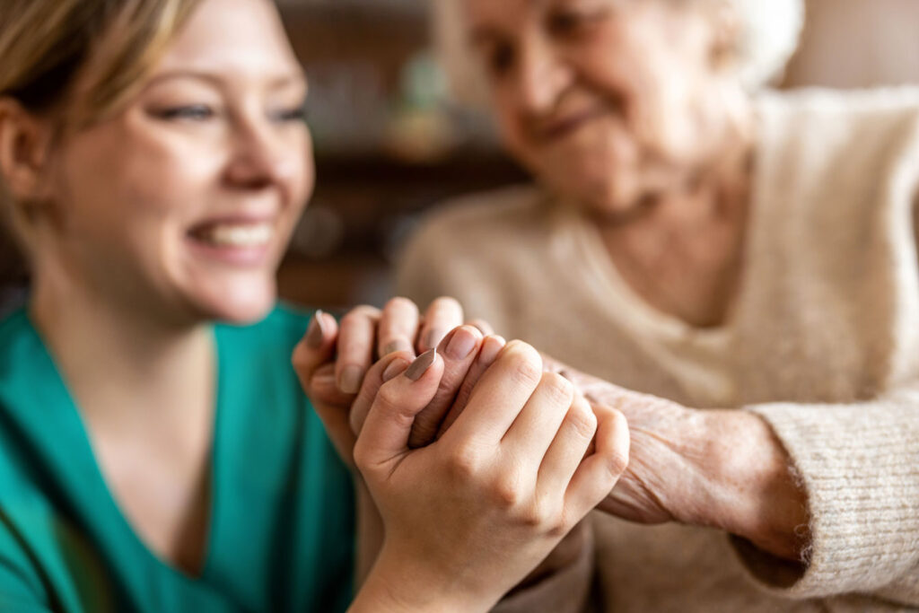 Carer holding an elderly ladies hand