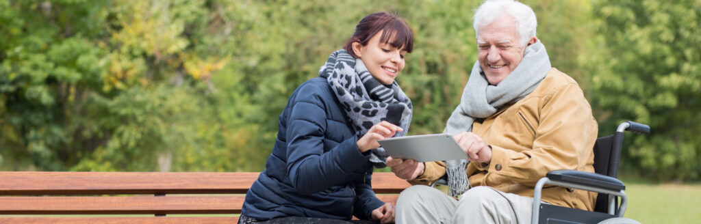 A lady helping an older gentleman on his ipad