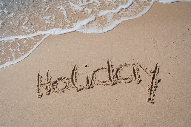 The word 'holiday' written in the sand on a beach