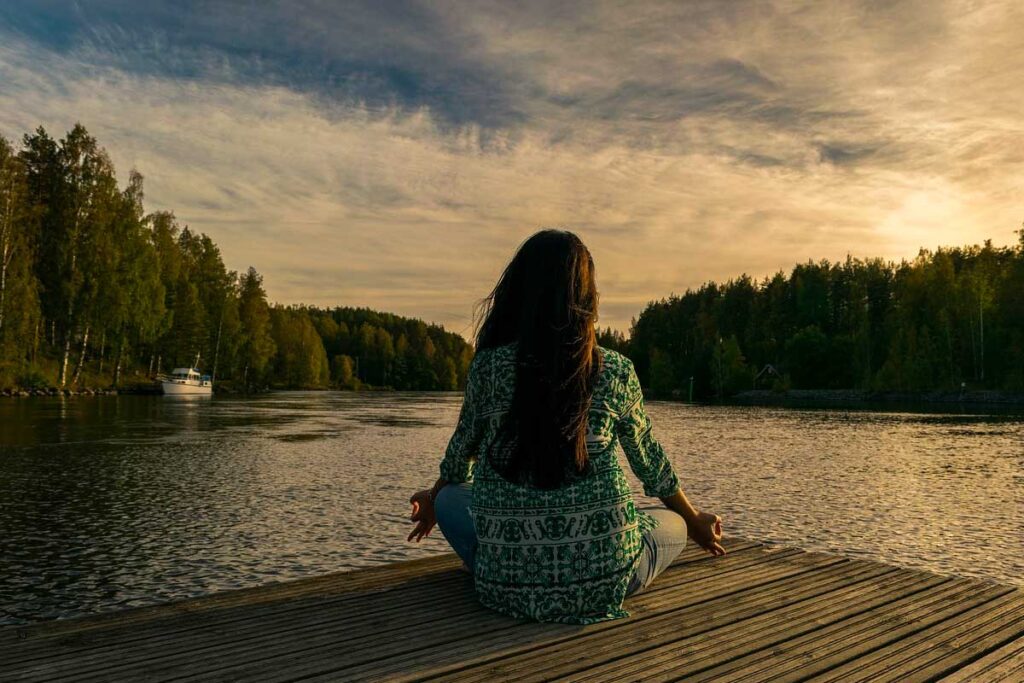 Person meditating by a lake